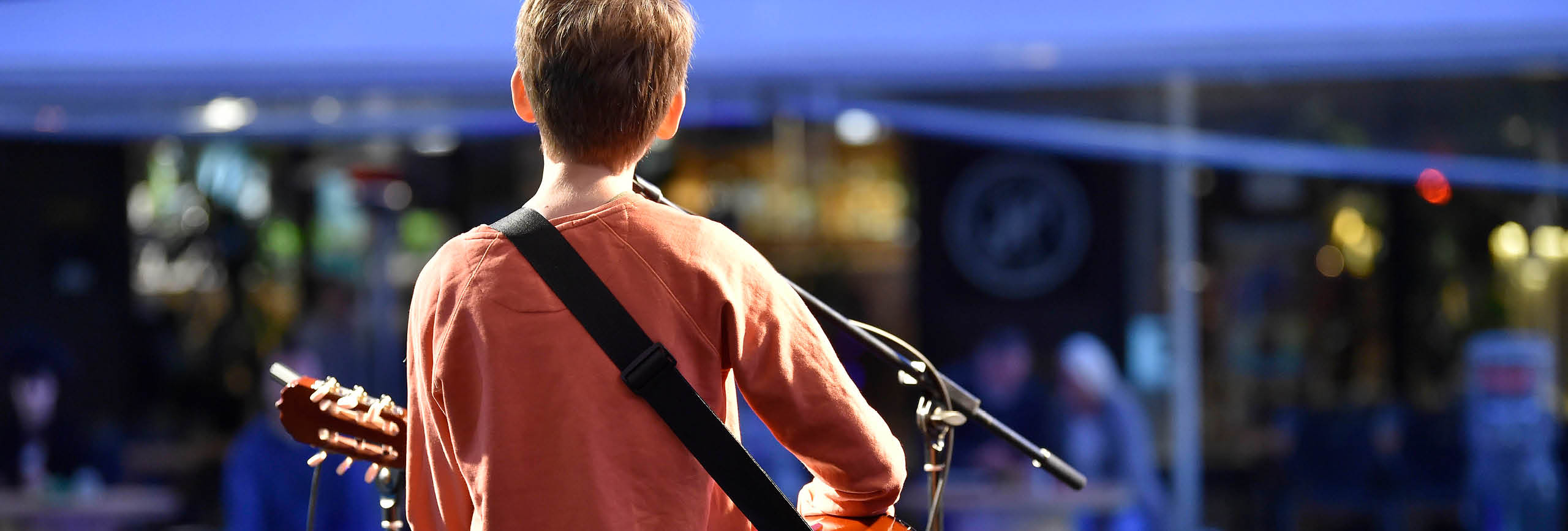 Boy playing guitar singing, from behind