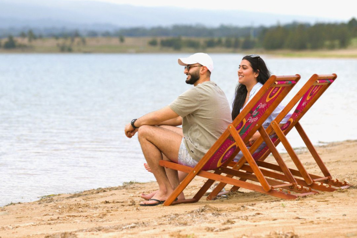 man and woman sitting on deck chairs at penrith beach