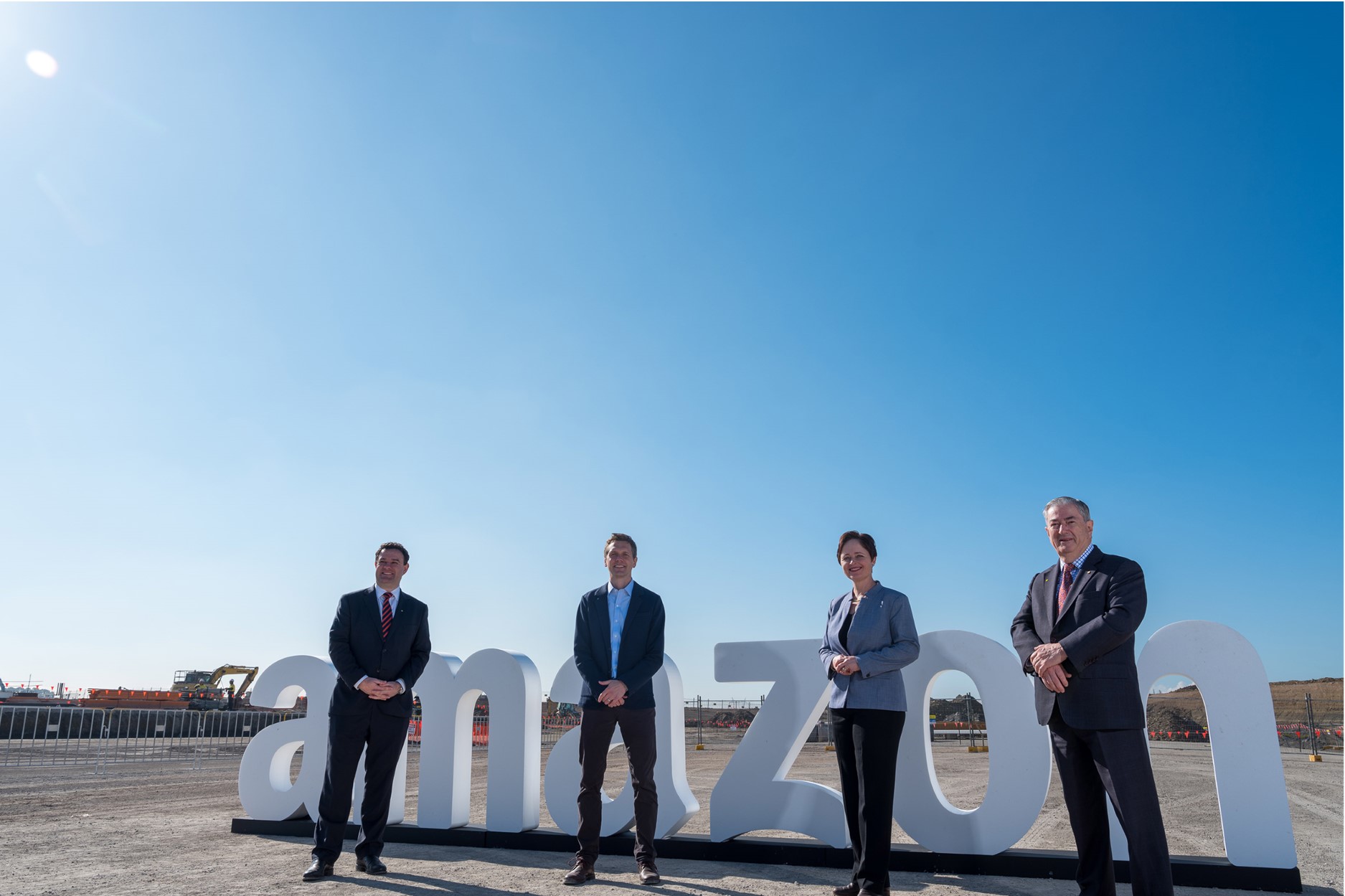 four people stand in front of large amazon sign