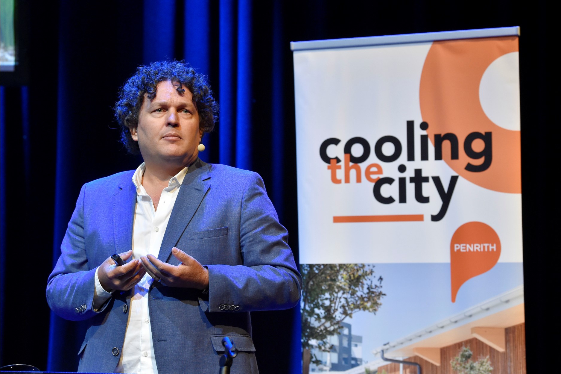 josh byrne standing on stage in front of cooling the city sign