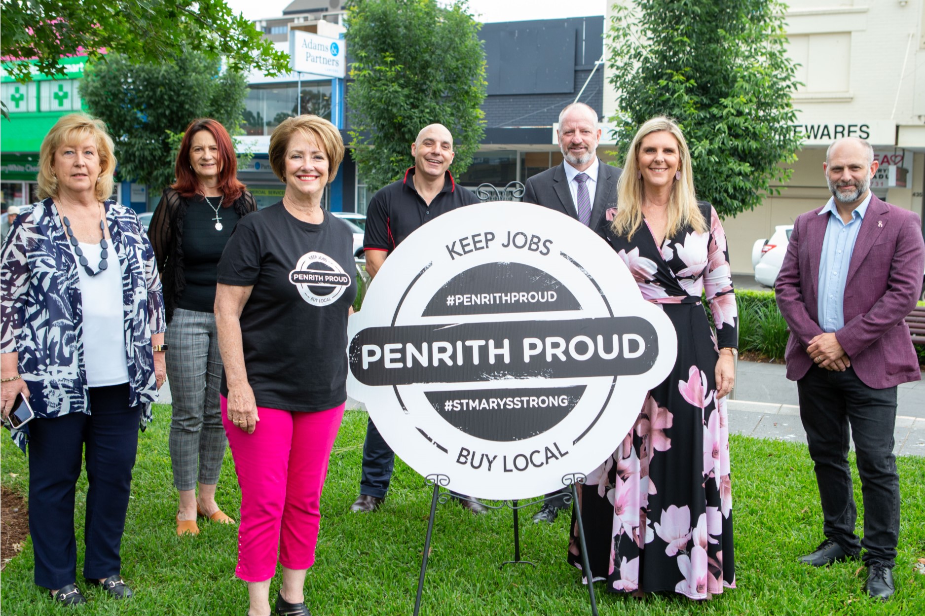 group of people standing near sign that says Penrith Proud