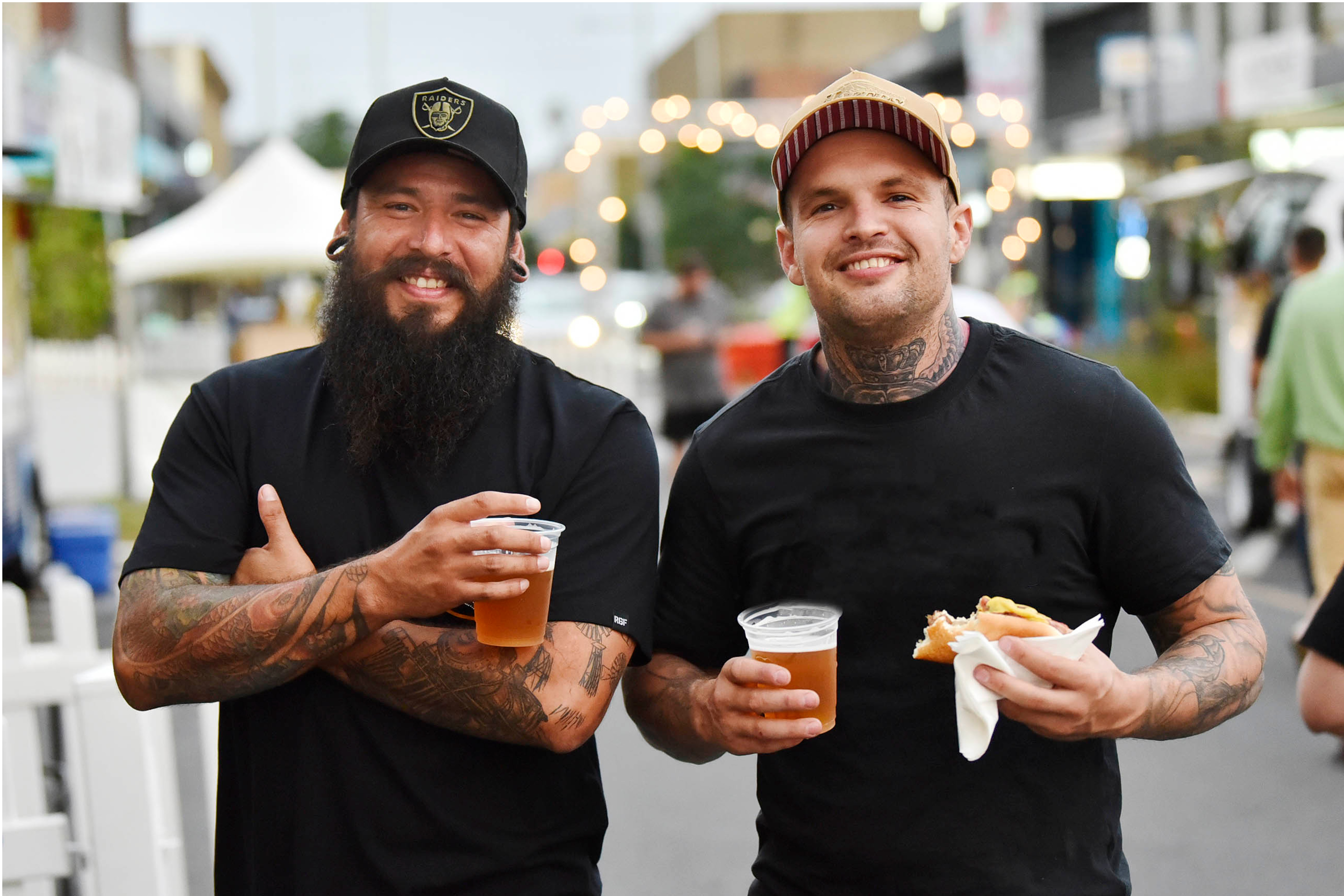 two men holding beers smiling