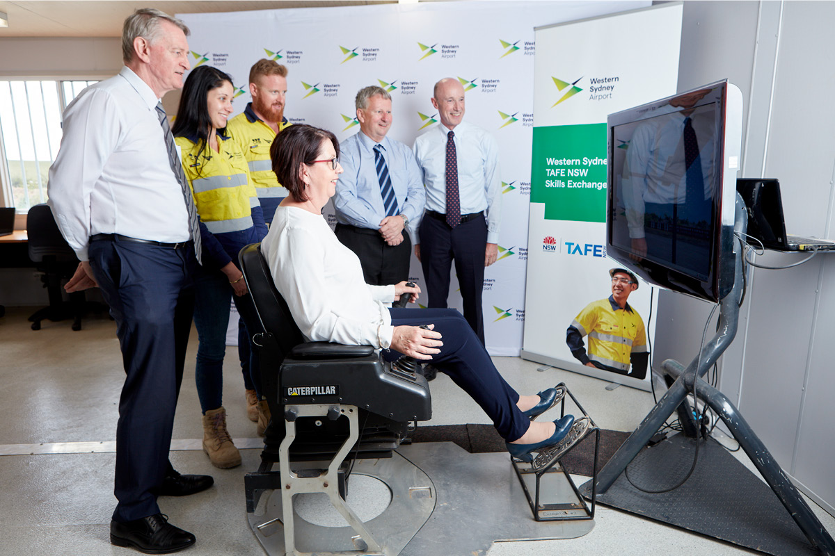 Western Sydney Airport and TAFE NSW leaders try their hand at an excavator simulator at the new on-airport Skills Exchange.