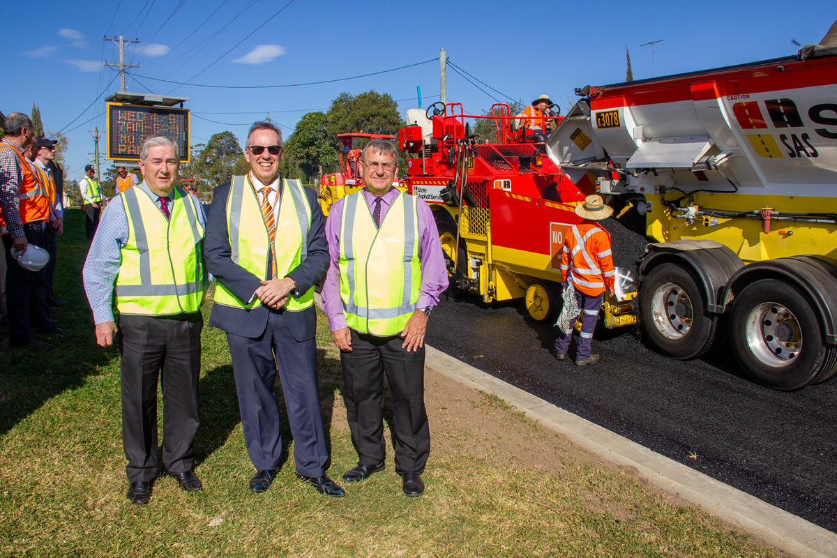 Mayor and staff at street with workmen laying glassphalt