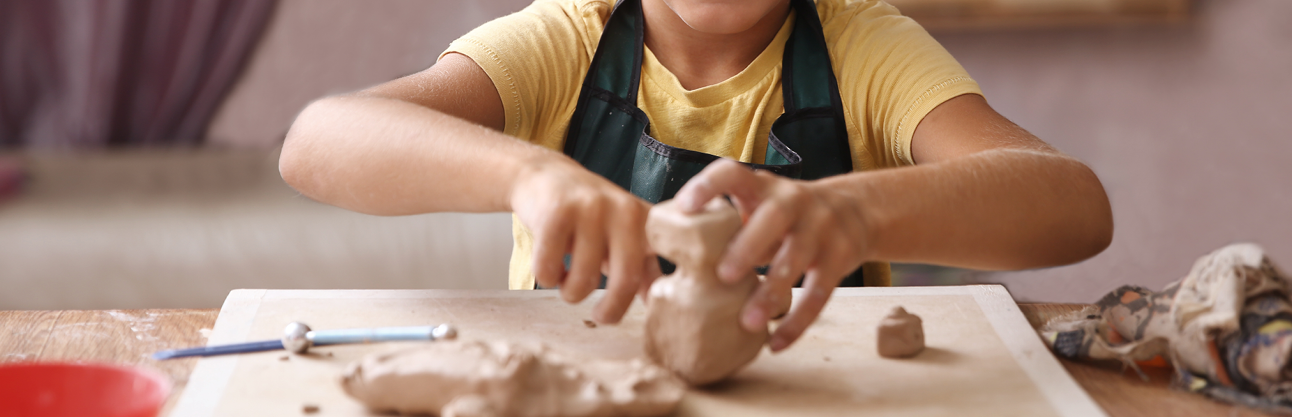 A child's hands using clay on a table.