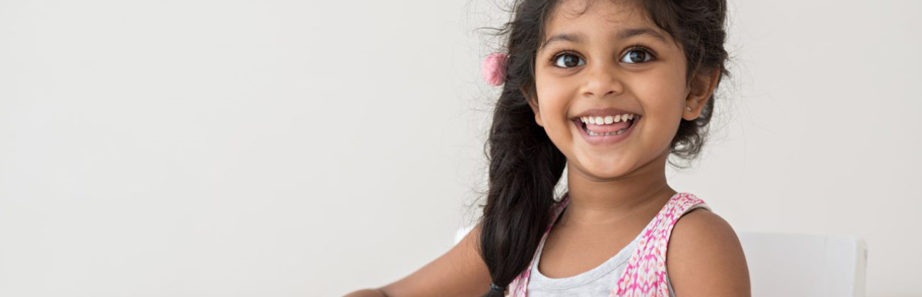 A little girl happily cutting some paper as an activity.