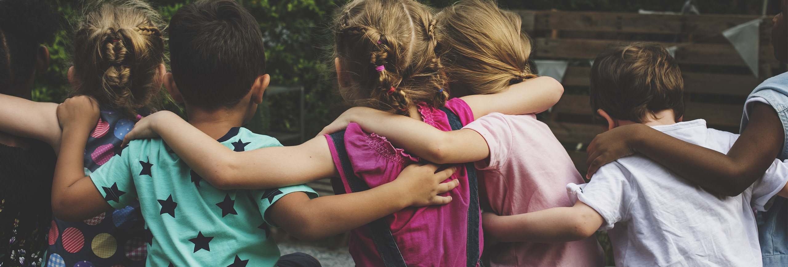 Rear view of children embracing in a row