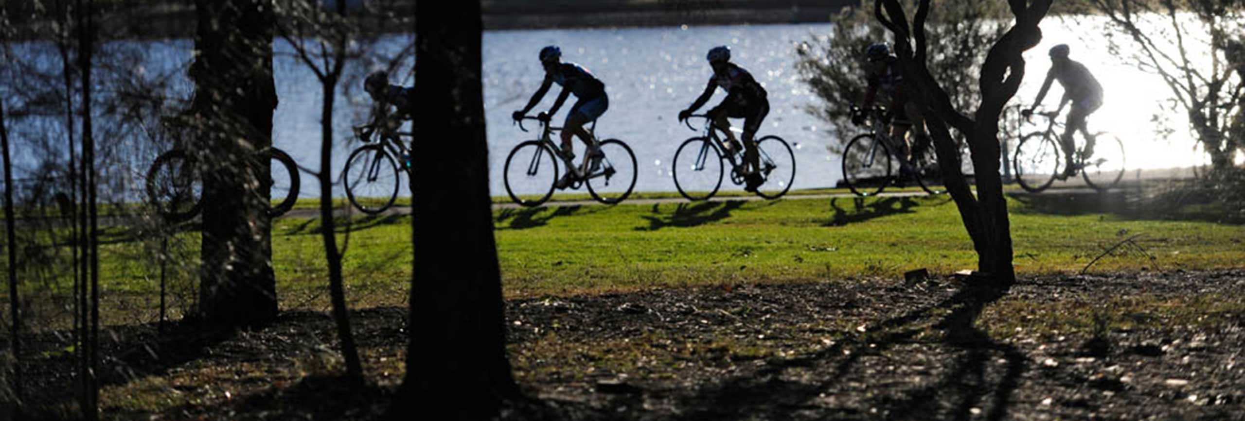 Group of cyclists riding on a path alongside the river