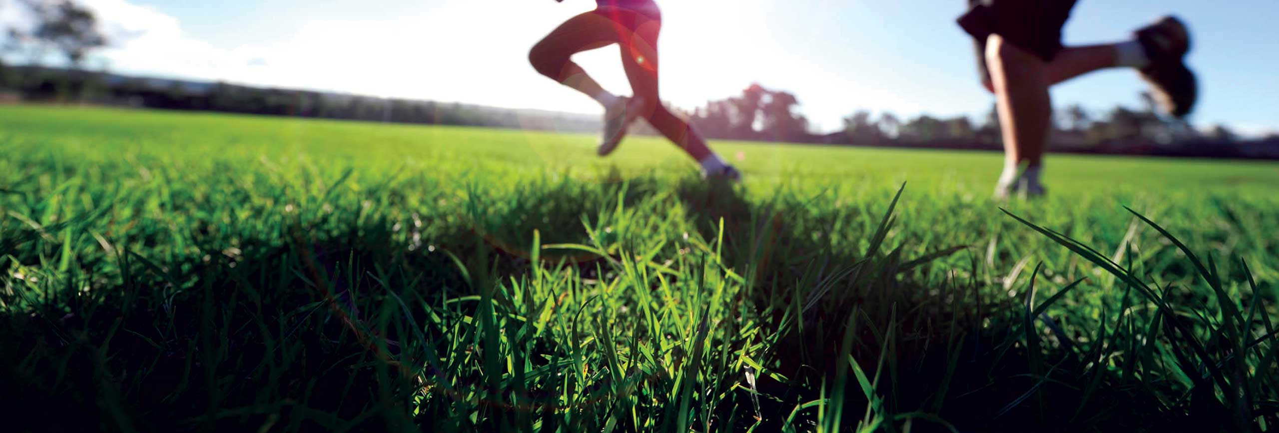 People running across the green grass